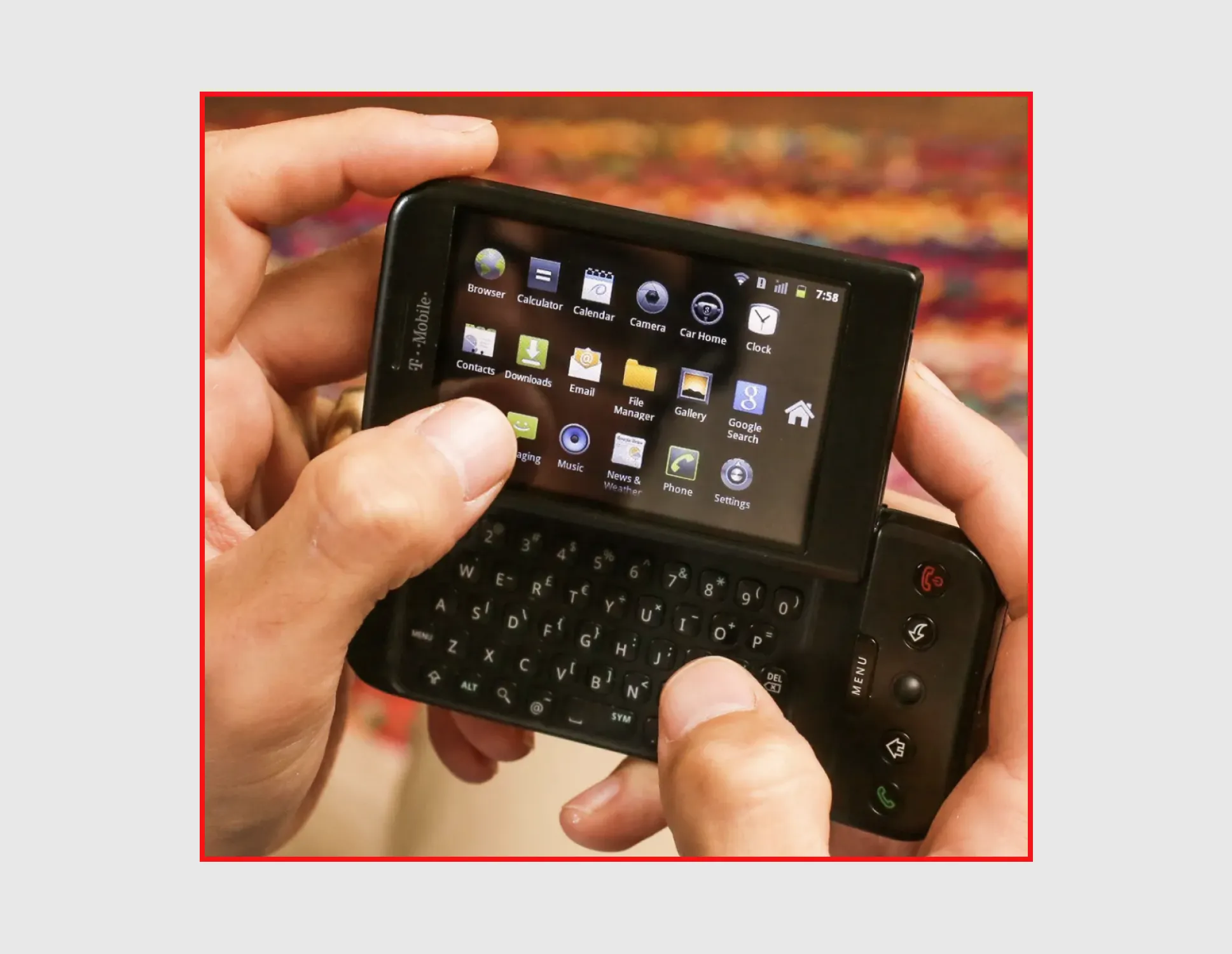 A T-Mobile G1 with its slide-out keyboard open and a crowded grid of app icons