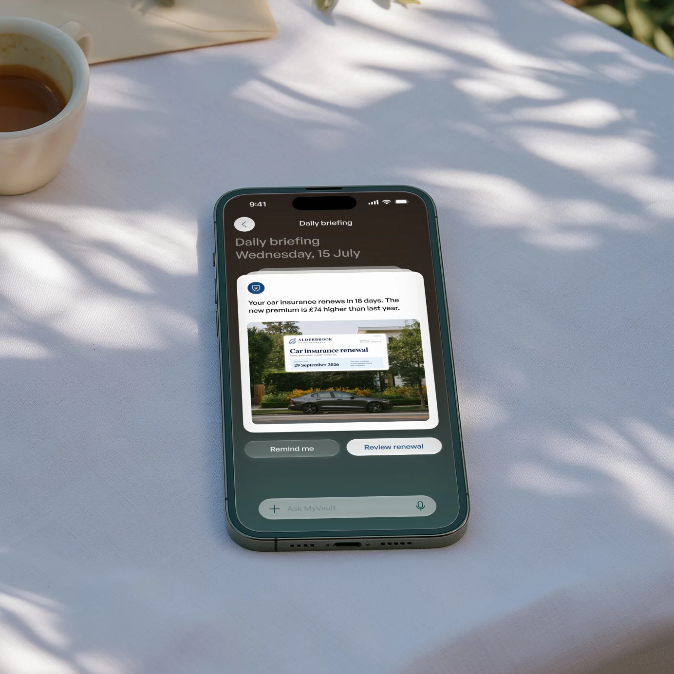 MyVault open on a phone on a linen tablecloth beside a coffee, showing the daily briefing